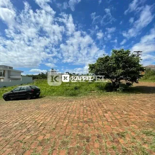 Vista externa de uma propriedade com um terreno gramado e um carro estacionado.