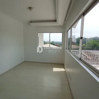 Interior de uma sala de estar com paredes brancas e piso claro.