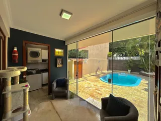 Sala de estar com porta de vidro que dá acesso a uma área externa com piscina.