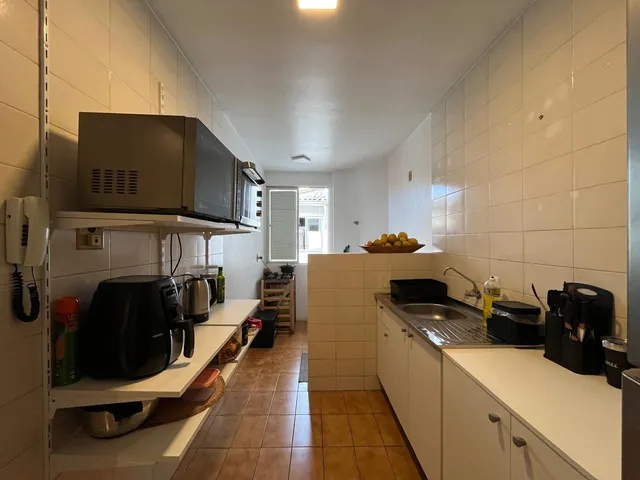 Cozinha com revestimento de azulejos brancos e bancada de trabalho.
