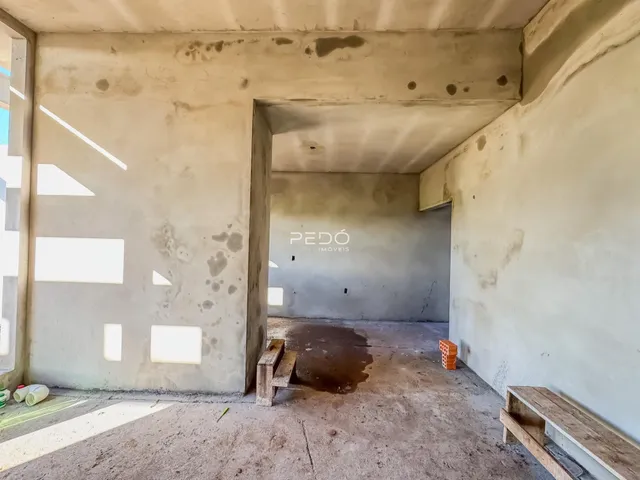 Interior de um espaço com paredes de concreto aparente e piso de concreto.