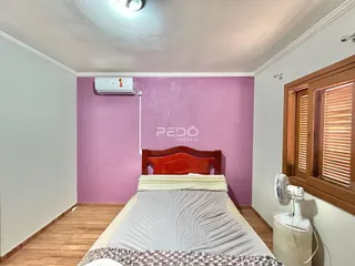 Quarto com cama de madeira e paredes em tom de rosa.