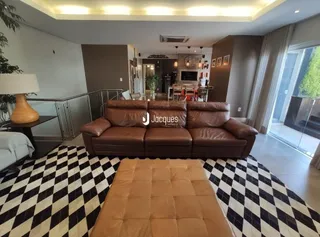 Uma sala de estar com um sofá de couro marrom e piso xadrez preto e branco.