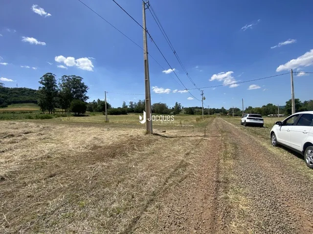 Vista de um campo aberto com vegetação e poste de luz em uma área rural.