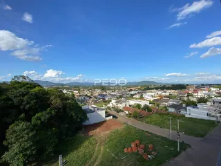 Vista aérea de uma área residencial com vegetação e construções no horizonte.