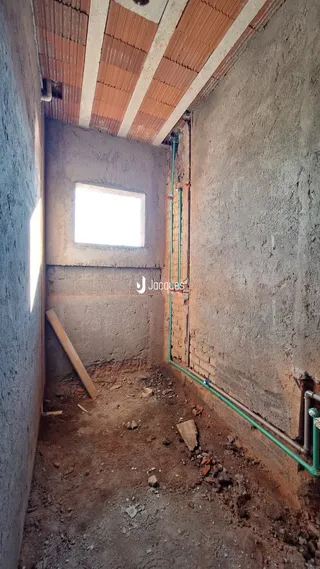 Interior de um espaço em construção com paredes de concreto e piso de terra.