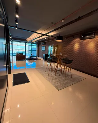 Sala de estar e jantar com piso claro e parede de madeira em um apartamento.