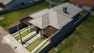 Fachada de uma casa moderna com telhado de telhas e área externa gramada.