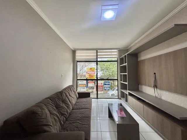 Sala de estar com sofá e janelão em um imóvel.