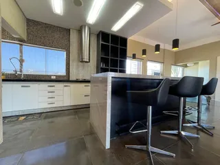 Cozinha moderna com armários brancos e ilha escura em um imóvel em Lajeado.
