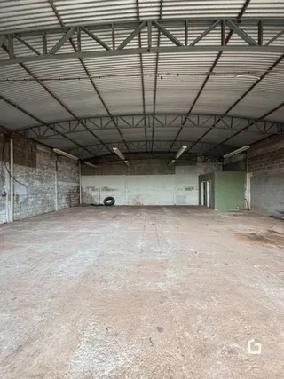 Vista interna de um espaço amplo com estrutura de telhado metálico exposta.