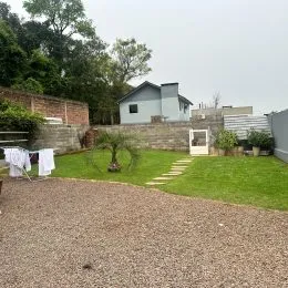 Foto da área externa com gramado e muro de pedra em uma propriedade.