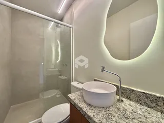 Banheiro com box de vidro e bancada de granito na residência.