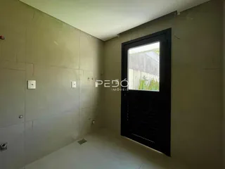 Vista interna de um corredor com paredes claras e uma porta escura.