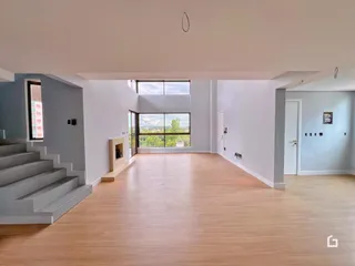 Ambiente interno de uma sala ampla com piso de madeira clara.
