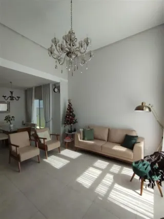 Sala de estar com sofá e lustre em ambiente claro.