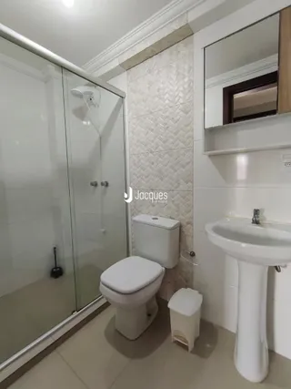 Foto de um banheiro com box de vidro, vaso sanitário e pia.