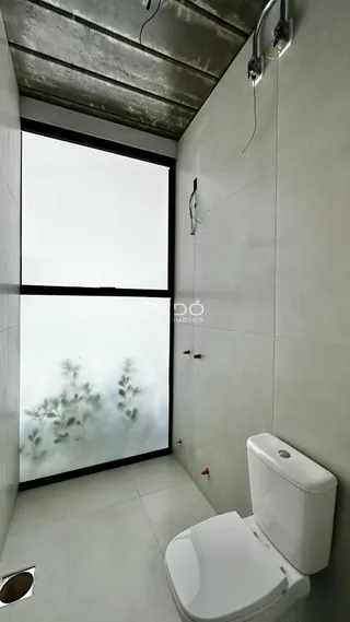Vista parcial de um ambiente interno com piso de cerâmica e vaso sanitário branco.