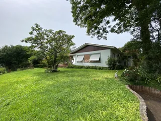 Vista externa de uma casa com grande gramado e árvores em Lajeado, Brasil.