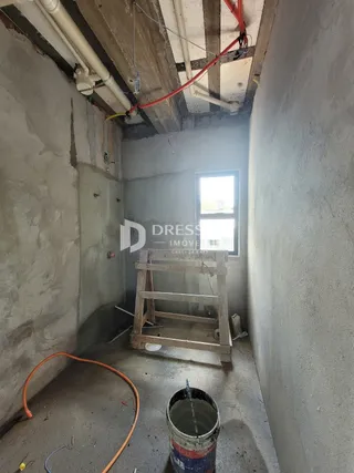Interior de um espaço com paredes de concreto e tubulações expostas.