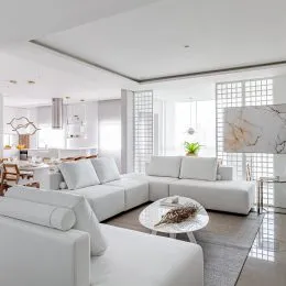 Sala de estar com sofá branco moderno e decoração clara.