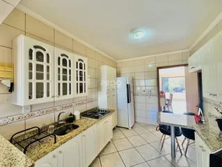Foto de uma cozinha com armários brancos e bancadas de granito.