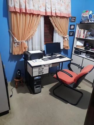 Foto de um ambiente interno com cortinas cor de laranja e uma estação de trabalho.