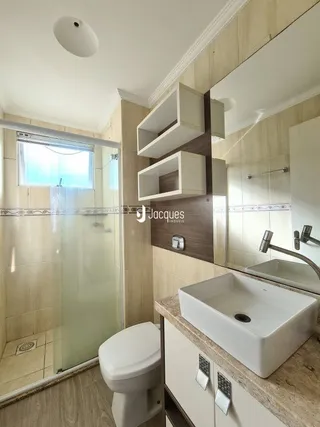Foto de um banheiro com revestimento cerâmico e bancada branca.
