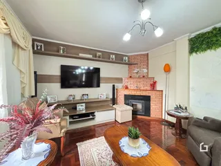 Sala de estar com lareira e piso de madeira em uma residência.