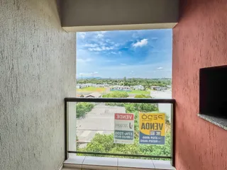 A janela exibe uma vista de campos e construções sob um céu azul.