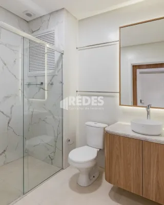 Banheiro moderno com box de vidro e armário de madeira.