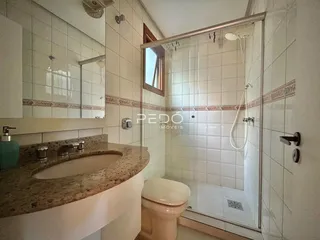Foto de um banheiro com revestimento cerâmico e box de vidro.