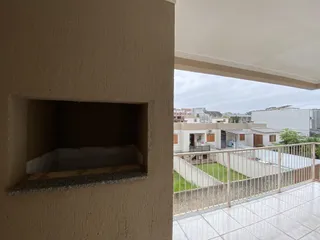Vista de uma área externa com grade de proteção e edifícios residenciais ao fundo.
