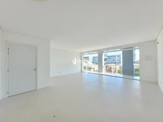 Ambiente interno de uma sala ampla com grandes janelas.