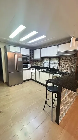 Cozinha moderna com armários brancos e bancadas escuras.
