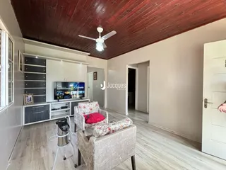 Sala de estar com piso de madeira e teto de madeira no imóvel em Lajeado.