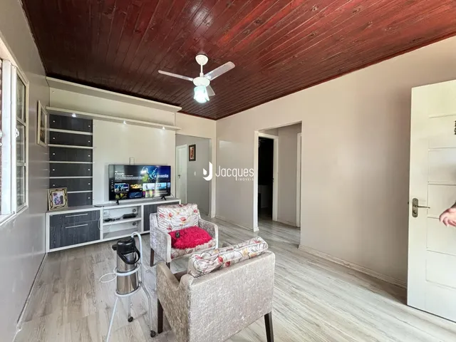 Sala de estar com piso de madeira e teto de madeira no imóvel em Lajeado.