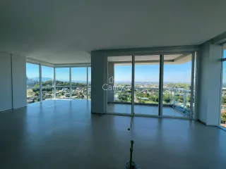 Uma sala ampla com grandes janelas oferece uma vista panorâmica da paisagem urbana.