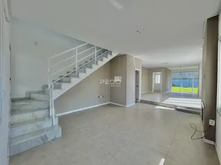 Interior de uma área ampla com escadaria e piso claro.