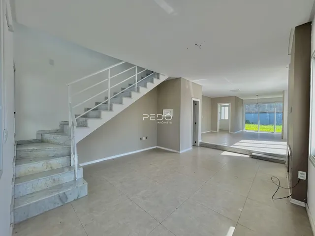 Interior de uma área ampla com escadaria e piso claro.