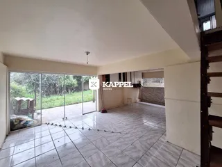 Sala de estar com piso de cerâmica e portas de vidro que dão acesso a um jardim.