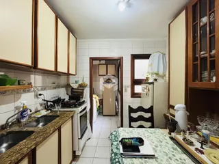 Foto de uma cozinha com armários de madeira e azulejos brancos.
