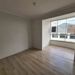 Ambiente interno com piso de madeira e grande janela.
