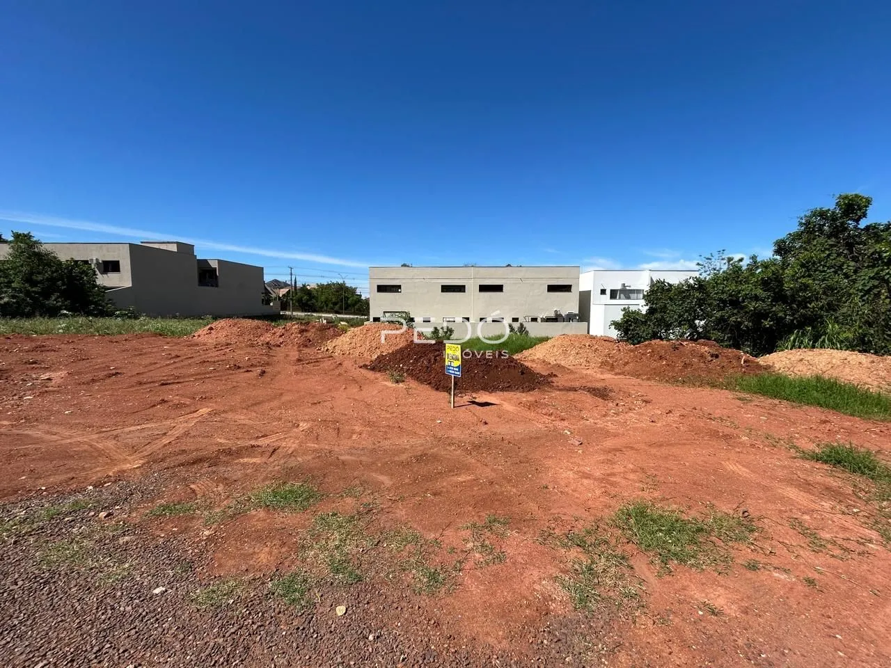 terreno em terra vermelha com construções em construção ao fundo