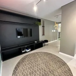 Foto de uma sala de estar com painel escuro e piso claro.