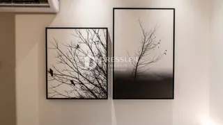 Uma fotografia de galhos de árvore emoldurados contra uma parede branca.