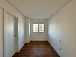 Vista interna de um ambiente com piso de madeira e paredes brancas.