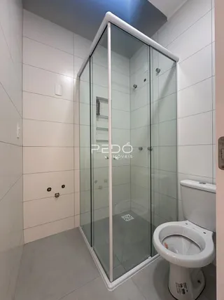 Banheiro com box de vidro e vaso sanitário em um imóvel.