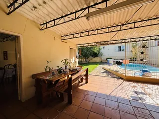 Área externa coberta com piso de cerâmica e vista para uma piscina.