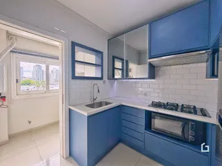 Cozinha moderna com armários azuis e revestimento de azulejos brancos.